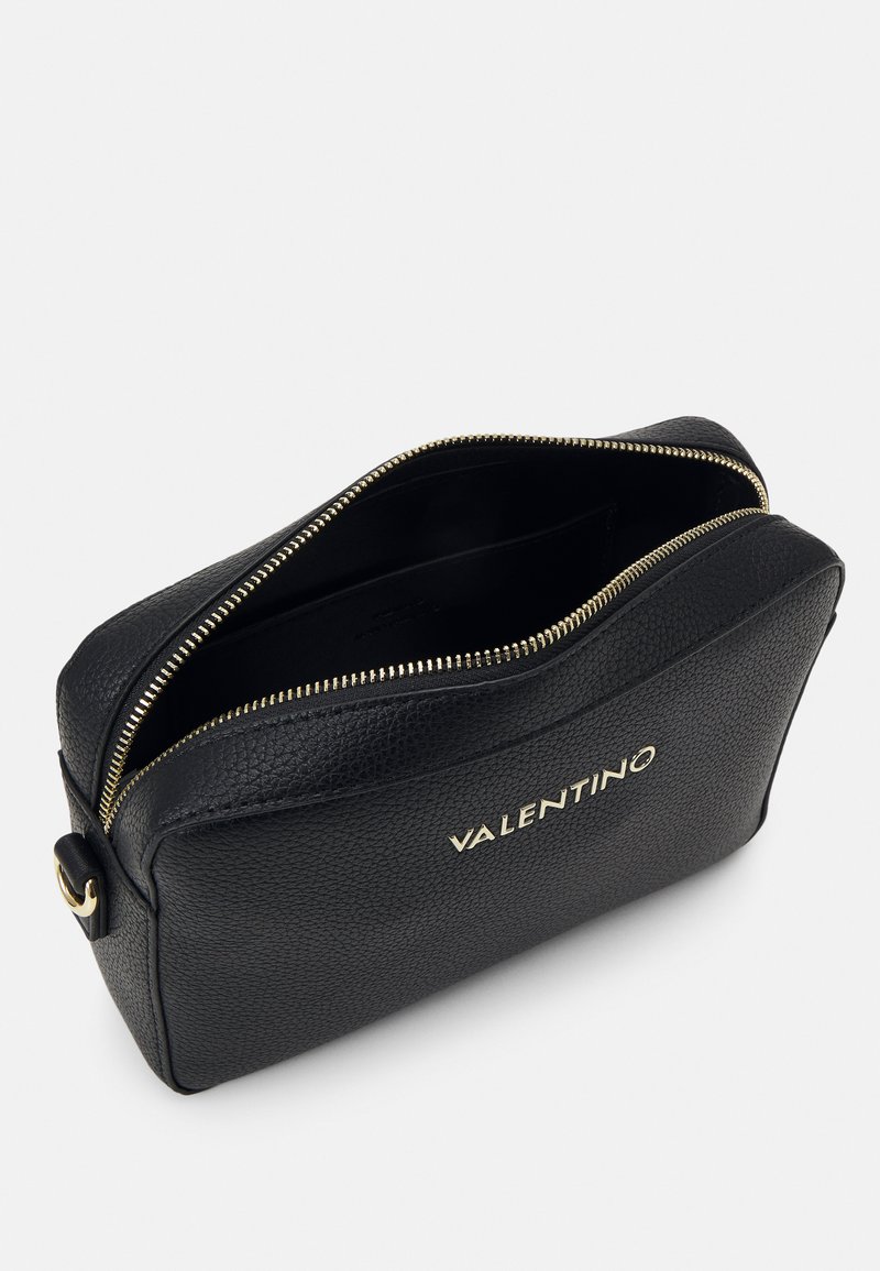 Schwarze Leder-Kosmetiktasche mit goldfarbener Reißverschluss, runder Form, genarbter Textur und "VALENTINO"-Logo in goldfarbener Prägung an der Seite.