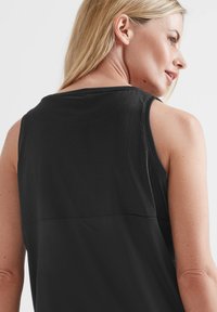 Black athletic tank top featuring a textured mesh upper section, smooth lower section, and a classic sleeveless design.