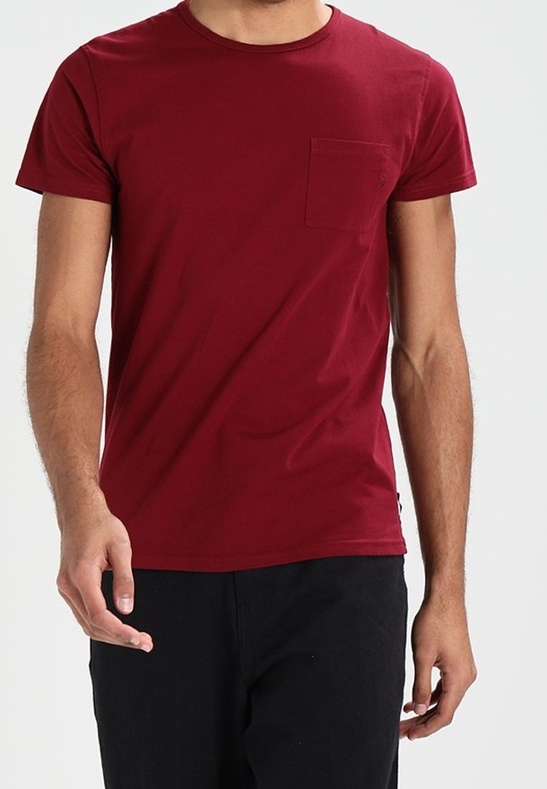 Camiseta de algodón burdeos con cuello redondo, mangas cortas y un bolsillo en el pecho izquierdo. Textura suave y diseño ajustado.