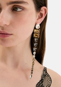 Eleganti orecchini lunghi con una sfumatura di pietre sfaccettate in trasparente, ambra e nero, con una punta appuntita per un design raffinato.