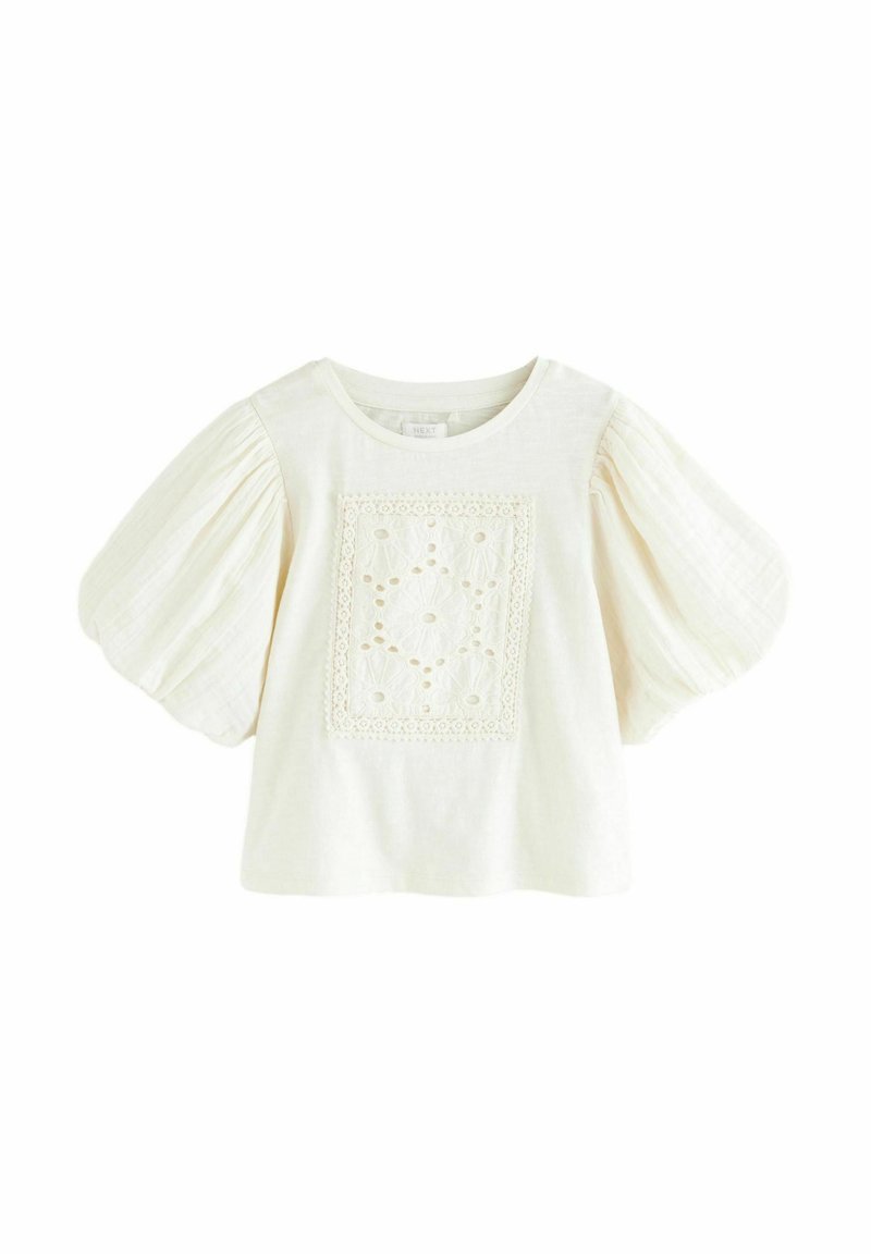 Haut à manches courtes de couleur crème avec un panneau carré brodé présentant des motifs floraux, des manches bouffantes et un col rond.