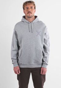 Felpa grigia in misto cotone, con tasca a marsupio frontale, cappuccio regolabile con cordino e una piccola grafica viola sul petto.