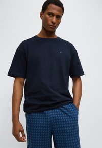 Μπλε βαμβακερό μπλουζάκι με στρογγυλή λαιμόκοψη και κοντά μανίκια, συνδυασμένο με μπλε σορτς με γεωμετρικό σχέδιο.