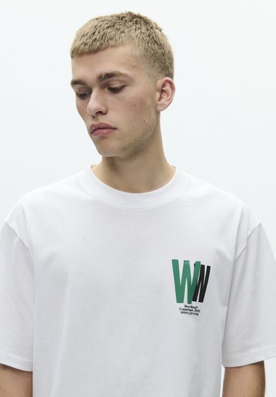 White cotton t-shirt with a round neck, featuring a graphic print of green and black letters "WW" on the left chest area.