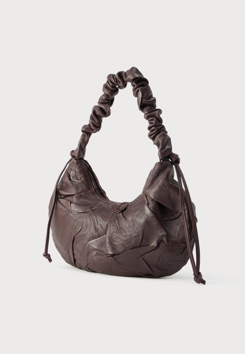 Brun læderhåndtaske med en krøllet tekstur, et samlet håndtag og justerbare snore. Har lynlåslukning for sikkerhed.