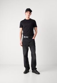 Černé tričko s logem "Bass", černý opasek, vybledlé černé džíny a černé tenisky. Kšiltovka je také černá. Jednoduchý design a střih.