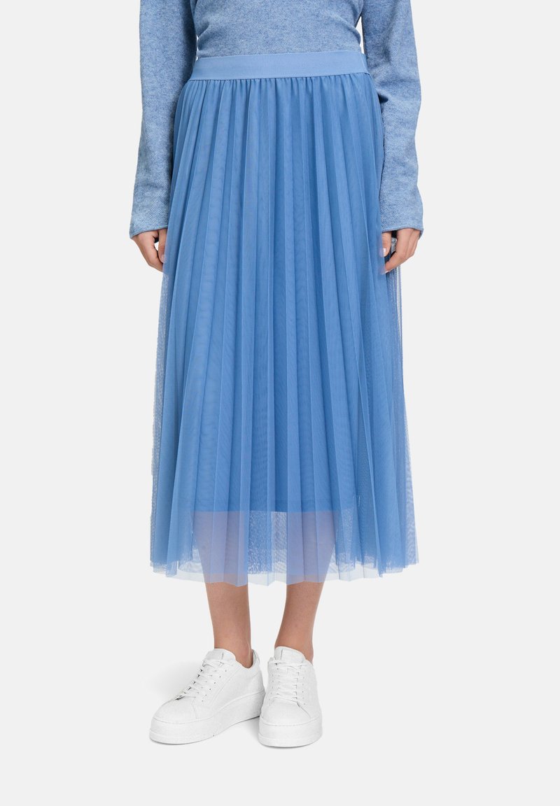 Gonna in tulle azzurro chiaro con design plissettato, vita elastica e lunghezza completa, abbinata a sneakers bianche, per un look stratificato e arioso.