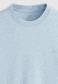 Lyseblå kortærmet t-shirt lavet af blødt stof, med rund halsudskæring og subtilt tekstlogo i en matchende farve på forsiden.