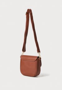 Brun lærcrossbody-veske med rund form, klaffelukking, gulldetaljer og bred skulderrem for justerbar bruk.