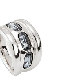 Anillo de plata con tres piedras preciosas de color gris oscuro. Diseño elegante y curvado con superficie pulida y surcos sutiles para textura.