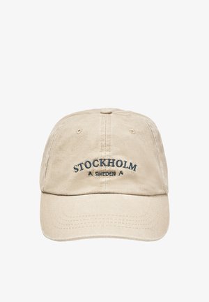 Beżowa czapka z daszkiem z wyszywanym tekstem "STOCKHOLM SWEDEN" na środku z przodu.