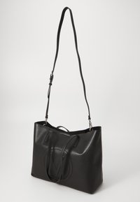 Svart läder tote-väska med en slät yta, med dubbla handtag och en cirkulär präglad logotyp. Justerbar axelrem ingår.