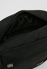 Borsa nera con motivo in rilievo, chiusura con zip e interno liscio. Presenta un piccolo etichetta con il marchio e accenti multicolore.