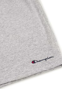 Graues Baumwoll-T-Shirt mit weicher Textur, kurzen Ärmeln und einem kleinen gestickten "Champion"-Logo in Marineblau und Rot auf der unteren linken Seite.