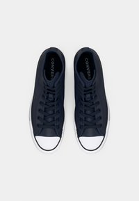 Tenisi înalți din pânză navy cu vârf și talpă din cauciuc alb. Au un sistem de șireturi clasic și un branding mare "CONVERSE" în interior.
