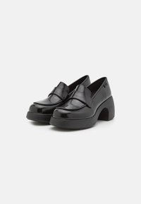 Black patent leather shoes with a rounded toe, a wide strap across the vamp, and a chunky heel. Smooth texture with a shiny finish.