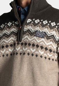 Gebreide trui met hoge kraag, voorzien van een geometrisch patroon in bruin-, crème- en zwarttinten; met ritssluiting en logo-opdruk.