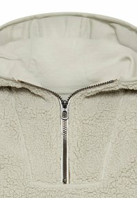Beige fleece hoodie met een hoge kraag, halve rits en een gestructureerde oppervlakte. Voorzien van een gladde binnenvoering en metalen ritshardware.