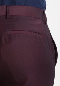 Burgundy skräddarsydda byxor med en slät textur, med en rektangulär bakficka och bälteshällor. Klassisk rak modell.