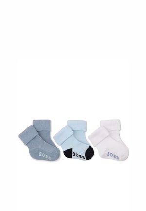 Trois paires de chaussettes pour bébé pliées en gris, bleu clair avec talons noirs et blanc, chacune avec le mot "Boss" sur la semelle.