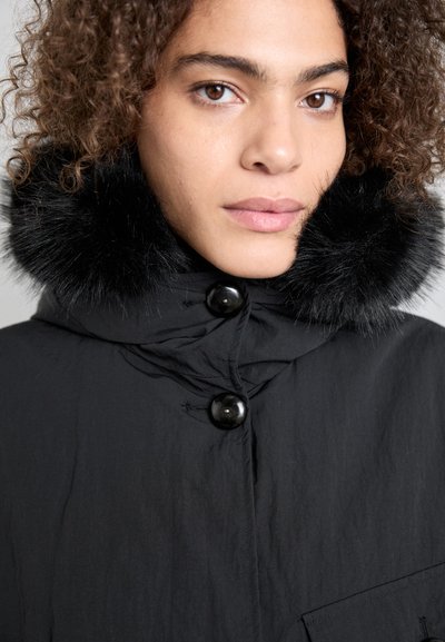 Black jacket with a hood featuring a faux fur collar. The material appears textured, with large black buttons and a front pocket detail.