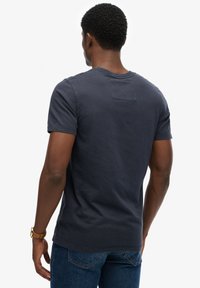 Mörkblå kortärmad t-shirt med rund halsringning och en liten detalj med bakficka, tillverkad av mjukt bomullsmaterial.