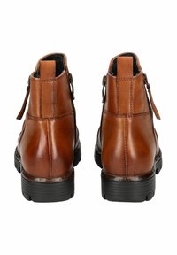 Bottines en cuir marron avec une texture lisse, zips latéraux et rainures horizontales sur des semelles en caoutchouc noir. Design à bout rond.