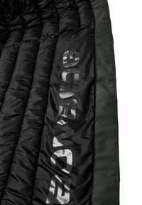 Zwarte pufferdeken met gestikte textuur en groene rand; voorzien van grote, reflecterende grijze branding langs één rand.