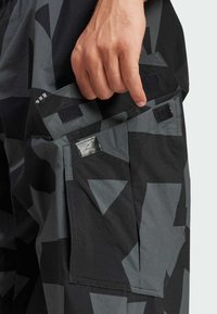 Cargo shorts met een geometrisch grijs en zwart patroon, gemaakt van lichtgewicht stof, met twee zijzakken en klittenbandsluitingen.