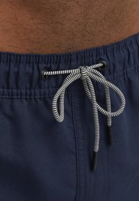 Bañador de marinero con cintura elástica, cordón negro y blanco, y una textura de tejido suave y ligero.