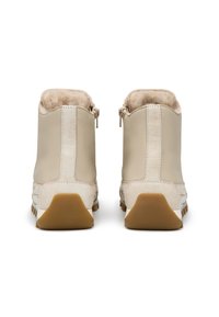 Botas de tobillo de cuero beige con un suave forro de piel de oveja beige y una suela de goma texturizada, con cierre de cremallera y detalles en contraste.