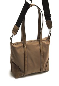 Bolso tote marrón hecho de cuero suave, con correas largas, un panel lateral textura y cierre de cremallera plateado en la parte superior.