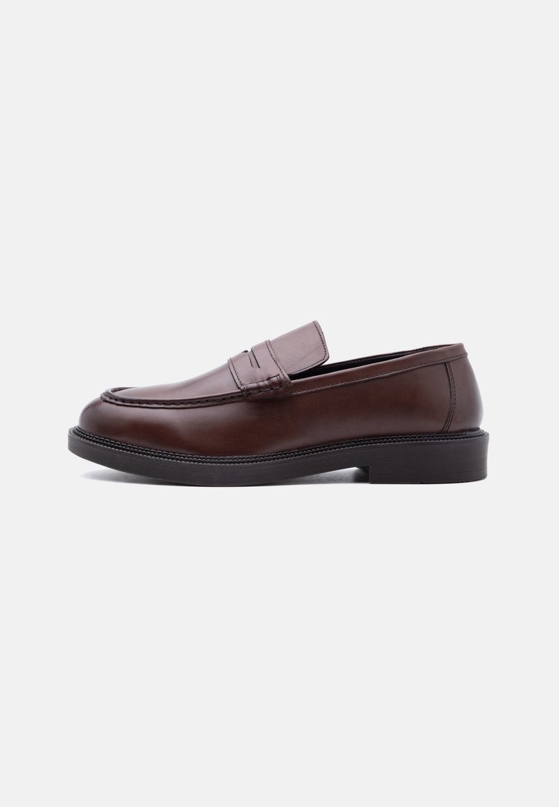 Mocassin en cuir marron avec semelle noire et détails surpiqués, présenté en profil latéral sur fond blanc.