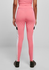 Rosa tights med høy midje, med hvite sidepaneler og svarte detaljer. Laget av elastisk materiale, designet for komfort.