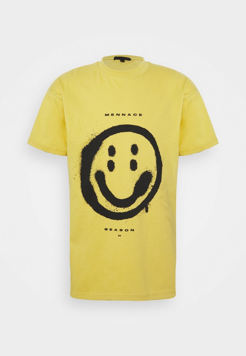 T-shirt jaune à manches courtes avec un grand smiley noir peint à la bombe et le texte « Mennace Season 21 » sur le devant.