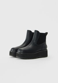 Black platform ankle boots with rounded toes and ribbed elastic side panels on a white background.