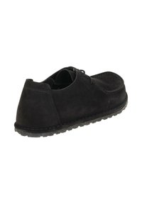 Zwarte suede casualschoen met dikke zool en achterstiksels, getoond vanuit een achterste hoek op een witte achtergrond.