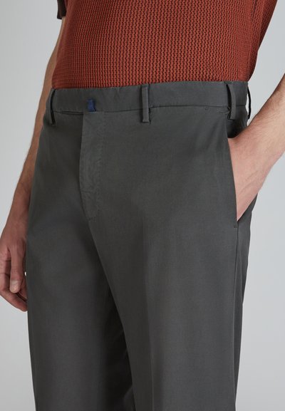 Pantaloni tailored grigio scuro con una texture liscia, dotati di tasche laterali e sottili dettagli di cucitura. La vita presenta un dettaglio ad anello blu.
