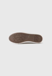 Brown rubber shoe sole with textured grip pattern and white edging; features diamond and horizontal lines for traction.