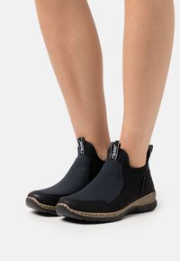 Zwart en marineblauwe enkelboots, met een gladde bovenkant, gestructureerde accenten, elastische zijpanelen en een rubberen zool met een decoratieve rand.