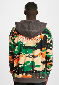 Hooded sweatshirt featuring a multicolored camo pattern in green, black, orange, and beige with elasticated cuffs and hem.