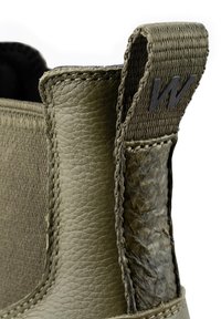 Zielonooliwkowe botki za kostkę z teksturowanej skóry i plecionego materiału. Wyraźna pętelka z tyłu z czarnym logo "W" oraz dekoracyjne przeszycia po bokach.