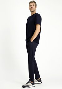 Camiseta de manga corta azul marino combinada con pantalones oscuros y zapatillas gris-negro. Textura suave, diseño simple y corte relajado.