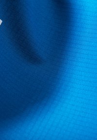 Tessuto blu texture con un motivo a griglia, che mostra una superficie liscia e una leggera lucentezza. Il colore si intensifica verso il fondo.