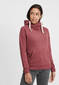 Felpa bordeaux con collo a imbuto, cordini crema e tasca frontale. Presenta polsi a coste e un'etichetta logo tessuta all'orlo.