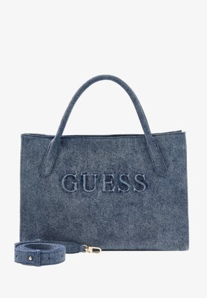 Denim tote bag with dual handles and detachable strap, embossed "GUESS" logo on front panel.