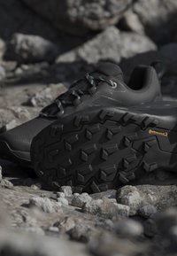 Scarpe da trekking nere con suole in gomma Continental battistrada poggiate su terreno roccioso.