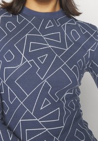 Námořnické tričko s dlouhým rukávem, které má geometrický bílý vzor. Hladký kulatý výstřih a přiléhavý střih s texturovanou tkaninou.