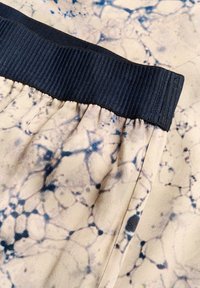 Elastic waistband in navy ribbed fabric combined with beige material featuring a marbled pattern in dark blue and black accents.