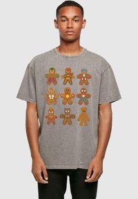 Camiseta de algodón gris de gran tamaño con un gráfico de figuras de jengibre en trajes de superhéroe, presentando colores diversos y diseños divertidos.